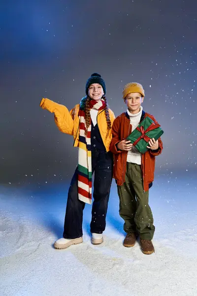 Two cheerful children are bundled in stylish winter outfits, delighting in the snowy atmosphere. — Stock Photo