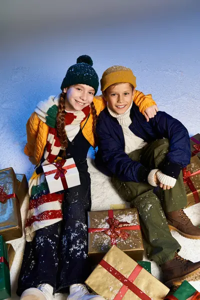 Two cheerful kids, warmly dressed, celebrate winter with smiles and gifts. — Stock Photo