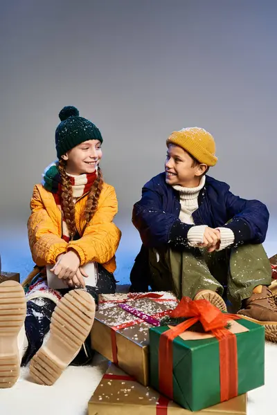 Children in warm clothing share joyful moments with presents during a winter celebration — Stock Photo