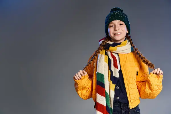 A young girl happily poses in bright winter clothing, radiating joy in a chilly atmosphere. — Stock Photo