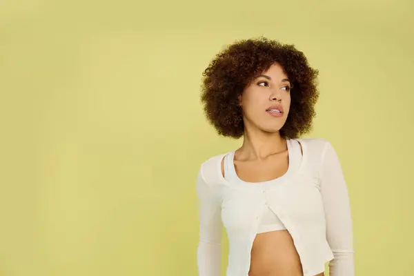 A young woman with curly hair stands confidently in her underwear in a bright setting. — Stock Photo