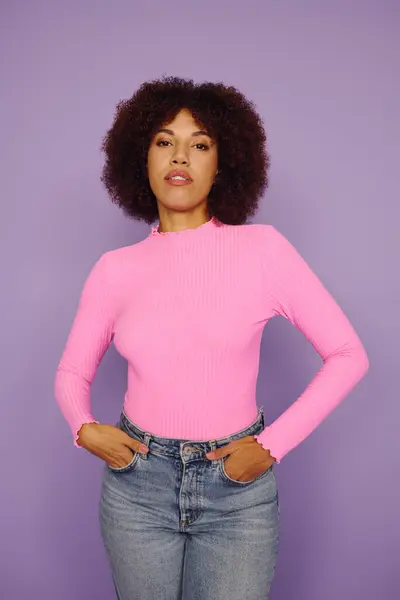 Uma jovem afro-americana com cabelo encaracolado confiantemente de pé em traje rosa. — Fotografia de Stock