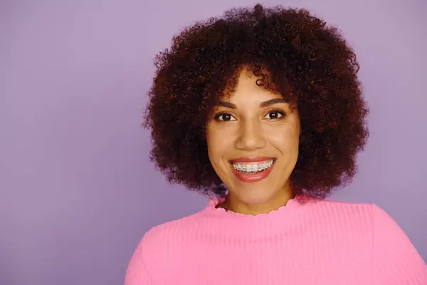 A young African American woman in pink casual wear radiates joy and confidence in a lively backdrop. — Stock Photo