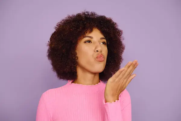 The young woman in pink effortlessly sending air kiss, framing her joyful expression beautifully. — Stock Photo