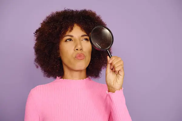 A young woman with curly hair poses thoughtfully, showcasing her emotions against a purple background. — Stock Photo