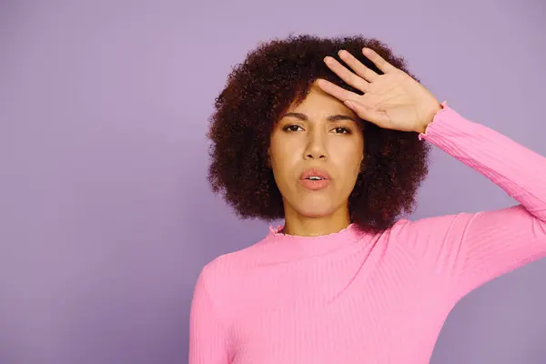 This expressive young woman with curly hair showcases her feelings while dressed in casual pink attire. — Stock Photo