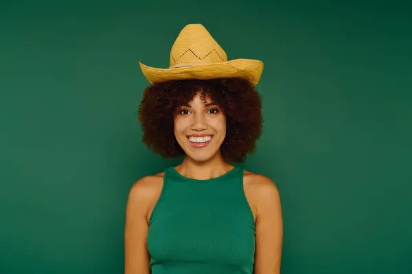 A smiling young African American woman in casual attire shows her lively personality against a green background. — Stock Photo