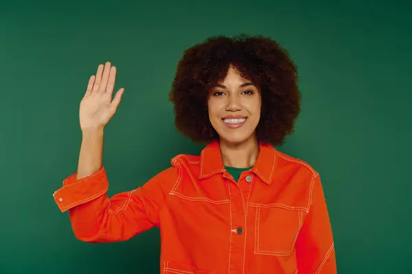 A cheerful young woman showcases her personality, raising her hand and radiating happiness in a lively setting. — Stock Photo