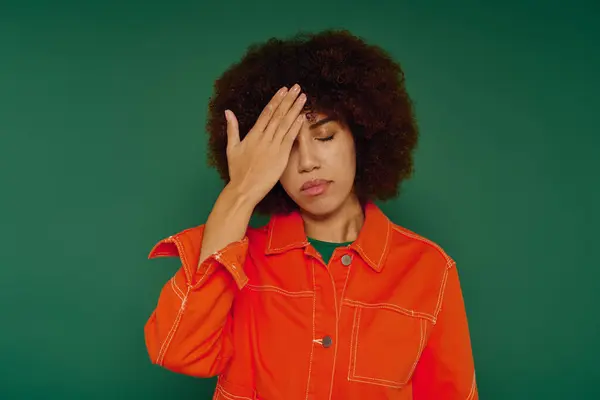 Embarrassed young woman, dressed casually, expresses her feelings while standing against a bright green backdrop. — Stock Photo