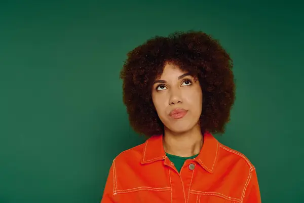 Una bella giovane donna mette in mostra le sue emozioni mentre vestita con disinvoltura di fronte a un vivido sfondo verde. — Foto stock