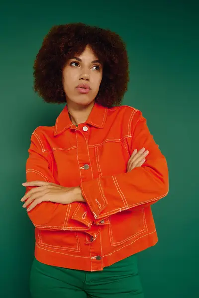 A pretty young woman with curly hair wearing casual clothing on a green backdrop. — Stock Photo