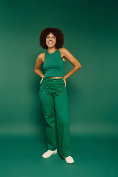 A young African American woman showcases her joyful emotion while standing against a vivid green background. — Stock Photo