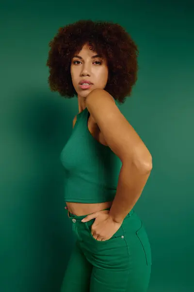 Una bella giovane donna indossa abiti casual davanti a uno sfondo verde. — Foto stock