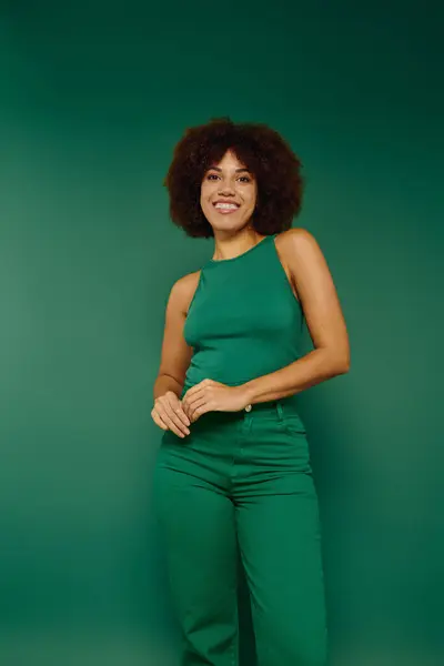 A cheerful young woman showcases her personality with curly hair, dressed casually in green, radiating happiness. — Stock Photo