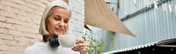 A stylish woman savors her warm beverage while sitting in a charming cafe decorated with plants. — Stock Photo