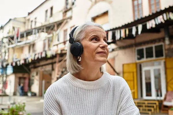 A joyful woman listens to music with headphones, appreciating the vibrant surroundings. — Stock Photo