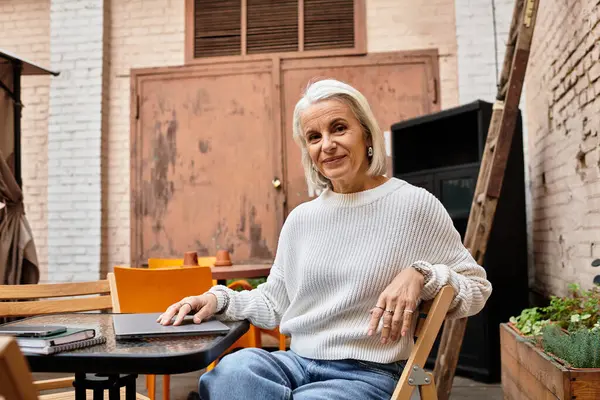 A beautiful woman with gray hair relaxes at a charming cafe, savoring her peaceful surroundings. — Stock Photo