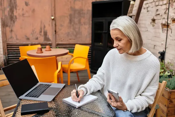 Brightly colored chairs surround a table as a woman thoughtfully writes in her notebook. — Stock Photo