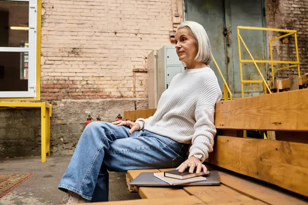 A stylish older woman sits comfortably on a bench, contemplating her surroundings in a unique space. — Stock Photo