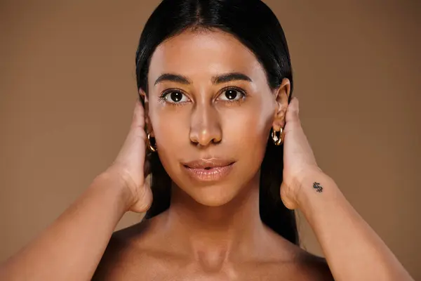 A stunning African American woman with brunette hair demonstrating skincare routines in a studio. — Stock Photo