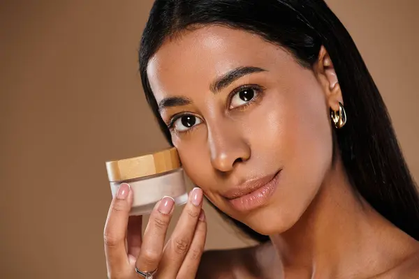 A stunning Black woman showcases skincare products in a studio, promoting self-care. — Stock Photo