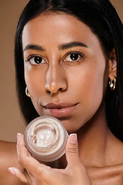 A woman with skin glowing holds a skincare product while promoting beauty diversity. — Stock Photo