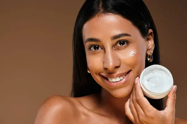 A woman with brunette hair showcases her skincare routine and beauty in a studio setting. — Stock Photo