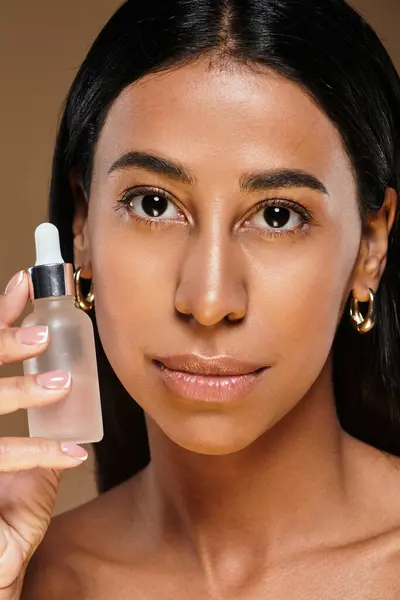African American woman demonstrates her skincare routine with a serum in a studio environment. — Stock Photo