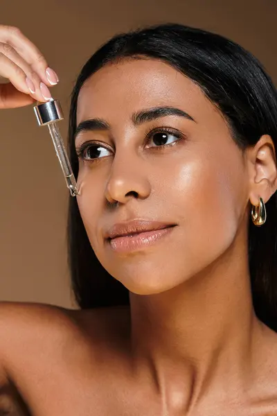 Una donna applica un siero per la cura della pelle al suo viso in un ambiente professionale da studio. — Foto stock