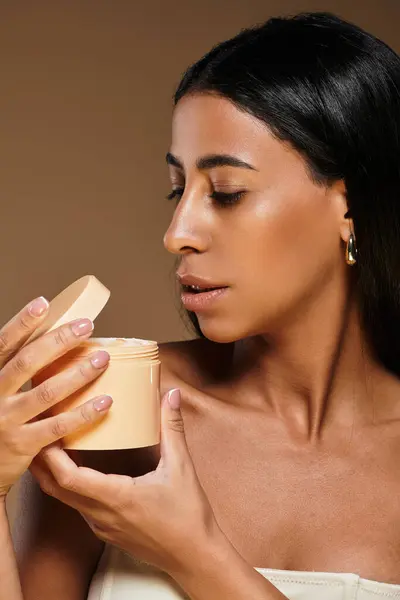 Donna afroamericana con capelli castani si concentra sulla cura del corpo utilizzando un prodotto per la cura della pelle in uno studio. — Foto stock