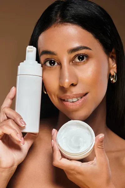 Una impresionante mujer afroamericana exhibe productos para el cuidado del cuerpo mientras promueve la diversidad del cuidado de la piel. - foto de stock