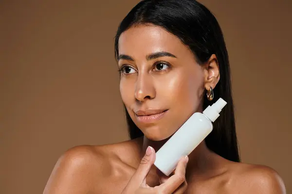 A woman with brunette hair highlights beauty diversity through skincare in a studio. — Stock Photo