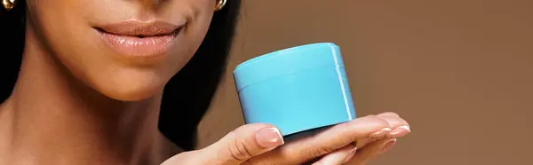 African American woman holds a skincare product while highlighting her beauty routine. — Stock Photo