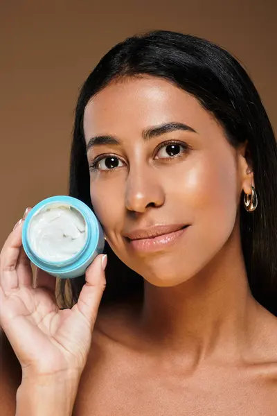 African American woman with brunette hair holds a skincare product, promoting beauty and diversity. — Stock Photo