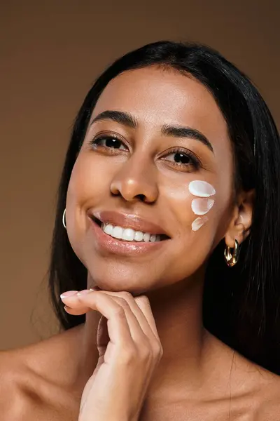 African American woman with brunette hair applying body care product in a studio environment. — Stock Photo