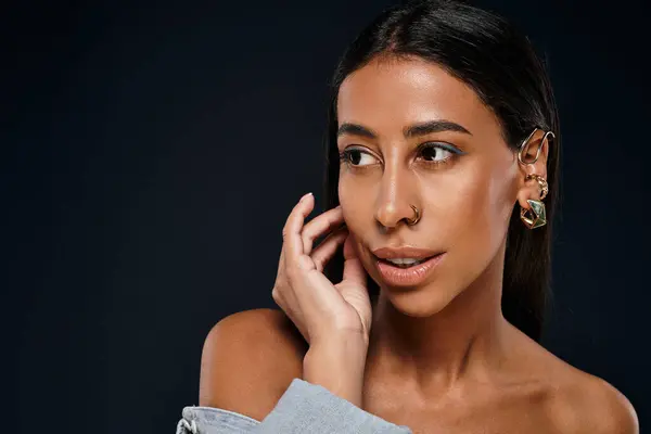 A woman with brunette hair showcases her jewellery in a studio setting. — Stock Photo