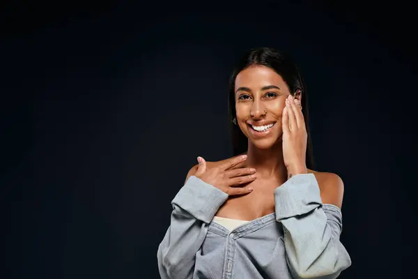 A woman highlights her skincare routine while smiling in a studio environment. — Stock Photo