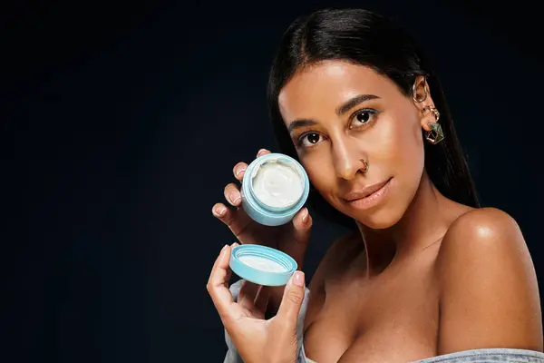 Mujer afroamericana con cabello moreno demuestra el cuidado corporal con el producto de cuidado de la piel. - foto de stock