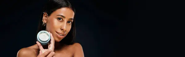 Una mujer con el pelo morena demuestra técnicas de cuidado de la piel en un entorno de estudio. - foto de stock