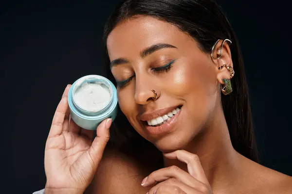 African American woman smiles while demonstrating her skincare routine in a studio atmosphere. — Stock Photo