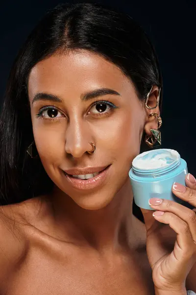 Una mujer afroamericana confiada muestra sus productos para el cuidado de la piel en un estudio profesional. - foto de stock