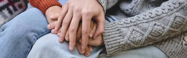 Two young, handsome people sit closely together, their hands intertwined in a warm display of affection. Surrounded by a cozy atmosphere, they enjoy each others company during a quiet moment. — Stock Photo