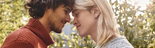In a vibrant park setting, Young loving gay couple lean in closely, their foreheads touching and expressing deep affection. — Stock Photo