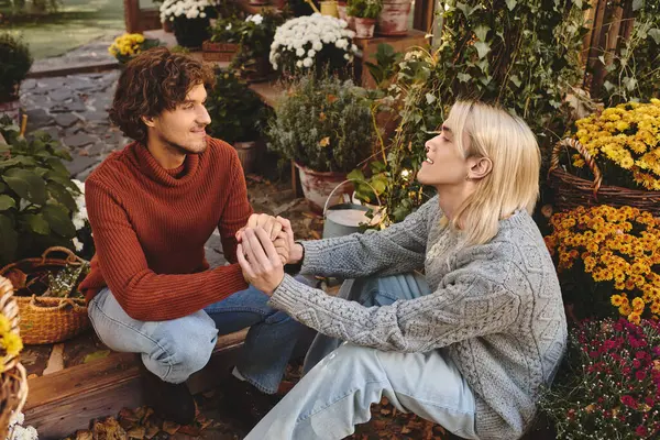 In a lovely garden filled with blooming flowers and greenery, two young partners enjoy a heartfelt connection as they hold hands. — Stock Photo