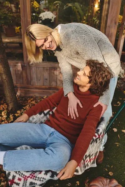 Young loving gay couple share a joyful and intimate moment in a garden filled with vibrant autumn leaves. The atmosphere is warm and inviting as they laugh and connect in a colorful setting. — Stock Photo