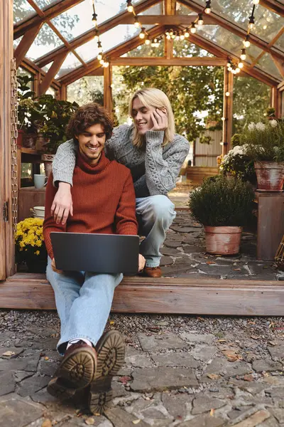 Two young men share a joyful moment in a lovely greenhouse filled with plants and flowers. — Stock Photo