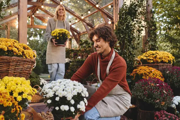 Dans un beau jardin rempli de fleurs colorées, les jeunes couples gays amoureux s'engagent joyeusement dans la culture des fleurs. Leurs sourires reflètent une passion commune pour l'horticulture, entourée par la beauté de la nature. — Photo de stock