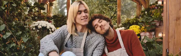 In a lush garden, Young loving gay couple relax among colorful blooms. With gentle smiles, they embody a heartfelt connection, capturing a serene moment of love and companionship amid natures beauty. — Stock Photo