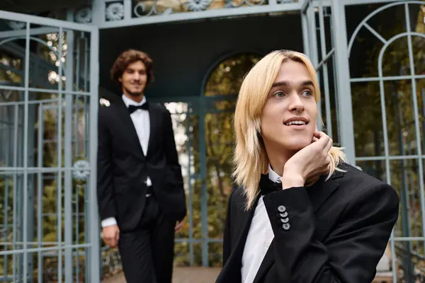 In a serene garden, two young men dressed in stylish tuxedos share a joyful moment. — Stock Photo