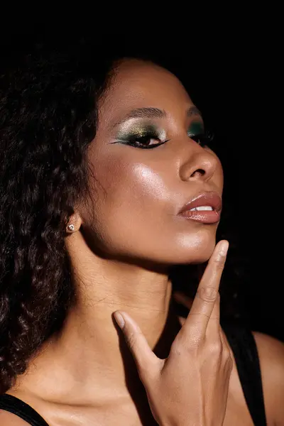 Una mujer confiada resalta su belleza con un maquillaje impresionante en un ambiente oscuro y dramático. — Stock Photo
